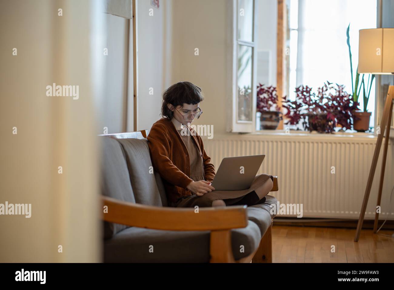 Adolescente concentrata che lavora, studia a casa in condizioni confortevoli utilizzando un computer portatile Foto Stock