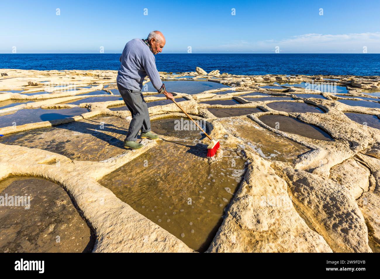 Żaren Darmanin, produttore di sale a Malta, dimostra la raccolta del sale nelle sue saline a Marsaskala. La raccolta avviene nei mesi caldi tra maggio e settembre. Saline di Darmanin vicino a Marsascala, Malta Foto Stock
