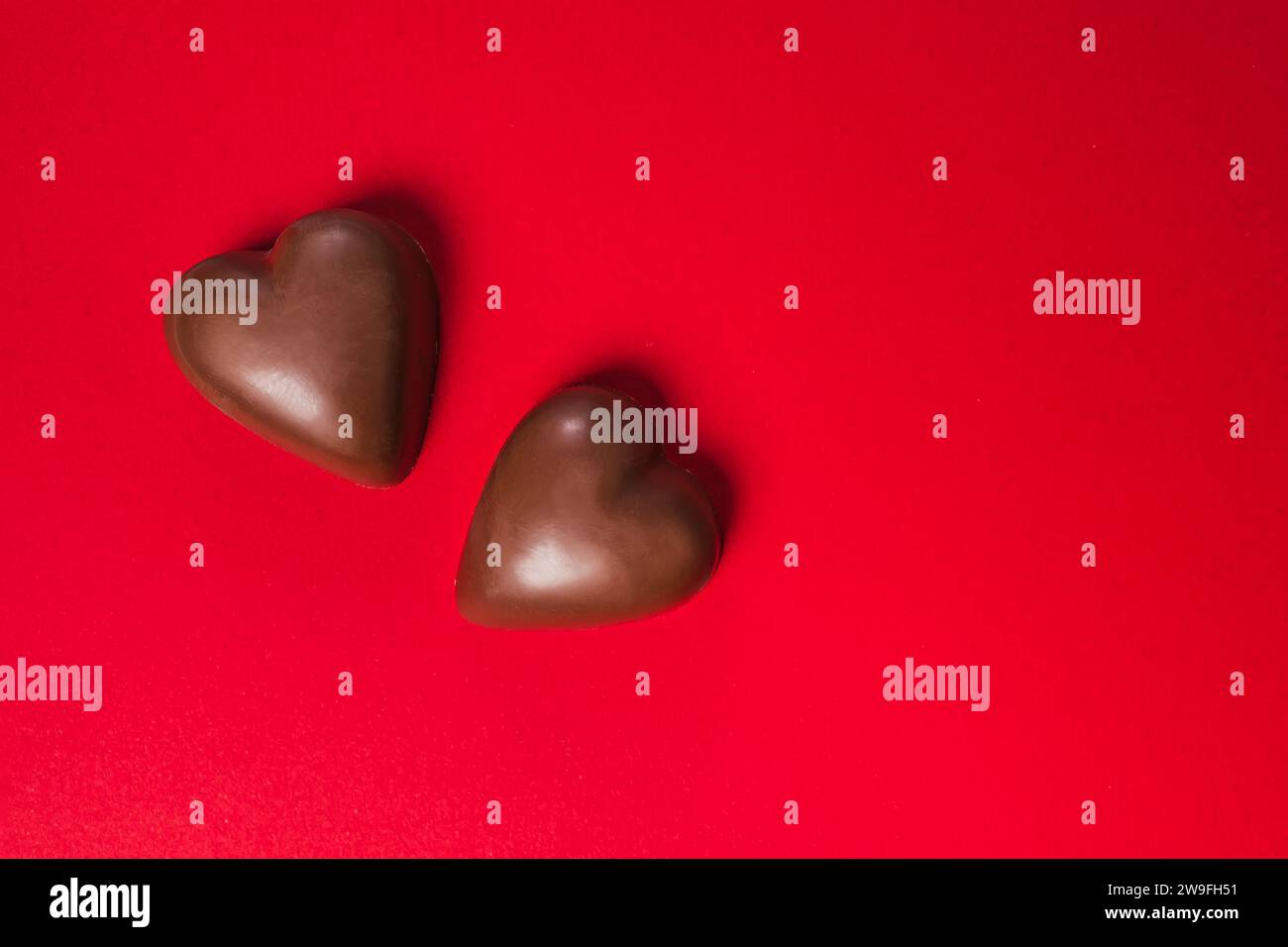 Due dolci al cioccolato a forma di cuore su sfondo rosso, dolcetti per San Valentino Foto Stock