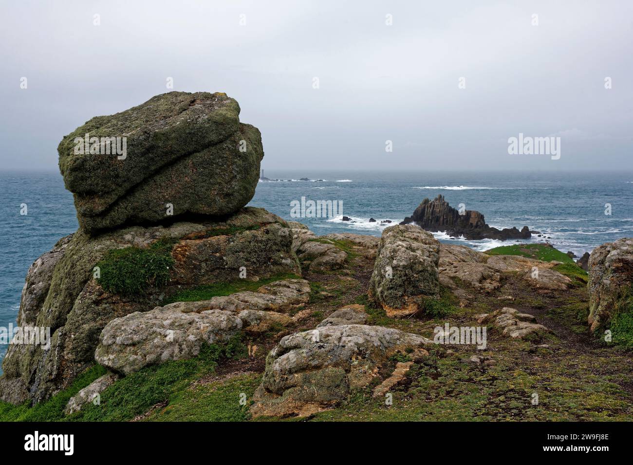 Granite Rock at Carn Cheer con Longships Lighthouse Behind, Zawn Wells, Land's End, Cornovaglia, Regno Unito Foto Stock