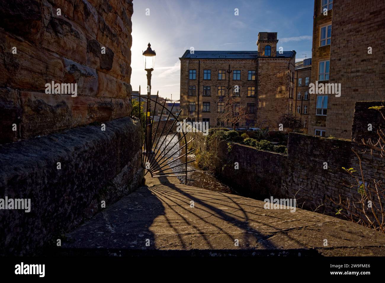 Un piccolo fiume attraversa un paesaggio urbano di edifici industriali storici convertiti lungo l'Eller Beck, Skipton, North Yorkshire. Foto Stock