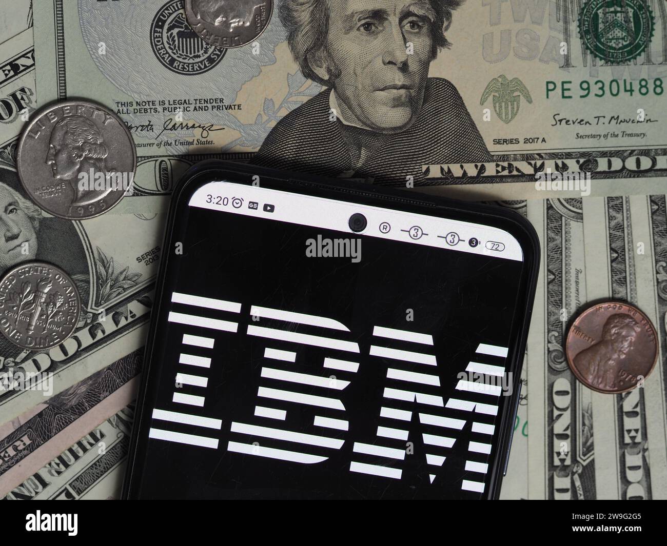 Baviera, Germania - 28 dicembre 2023: In questa foto, un logo IBM visibile su uno smartphone con banconote e monete in dollari statunitensi Foto Stock