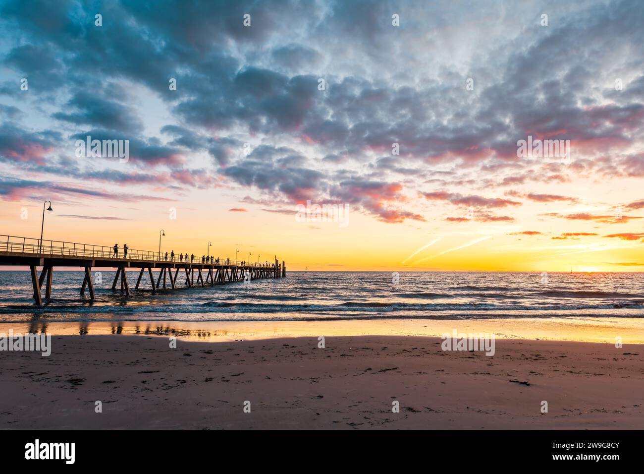 Il molo di Glenelg Beach ha una silhouette con persone che camminano al tramonto, Adelaide, Australia meridionale Foto Stock
