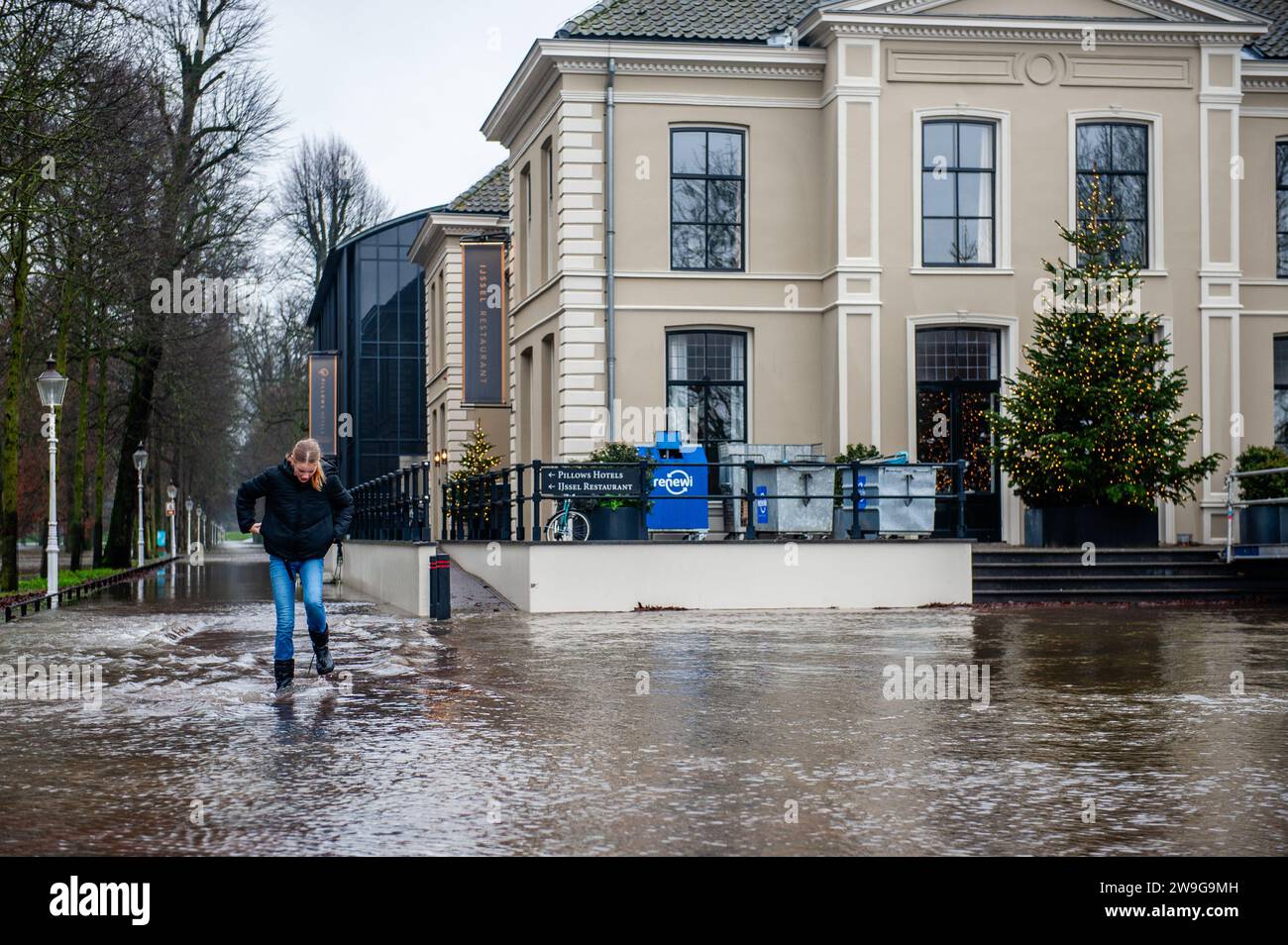 Deventer, Paesi Bassi. 27 dicembre 2023. Una ragazza è vista giocare sull'acqua in un'area allagata. A causa dell'innalzamento dell'acqua nel fiume IJssel, il comune del Deventer sta posizionando sacchi di sabbia sulla banchina per proteggere il centro storico della città. Le forti piogge che sono cadute in questi ultimi mesi, unite al fatto che le Alpi sono insolitamente calde per questo periodo dell'anno, hanno creato il fiume IJssel che inonda a Overijssel, Gelderland, Drenthe, Brabante e Limburgo. Credito: SOPA Images Limited/Alamy Live News Foto Stock