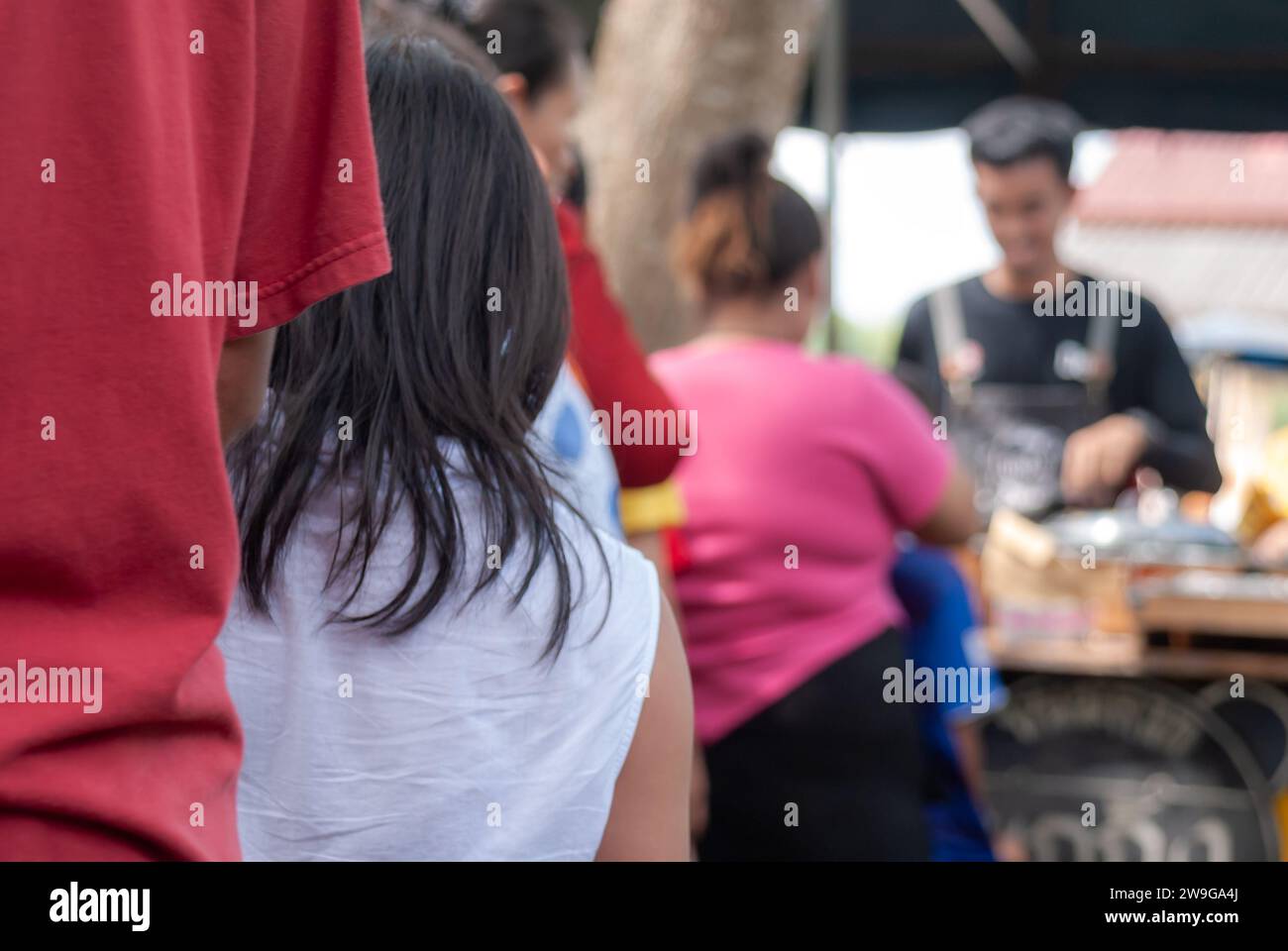 Persone in attesa di ricevere la distribuzione di cibo alle persone che vengono al festival di Kathin per fare il merito in Thailandia Foto Stock