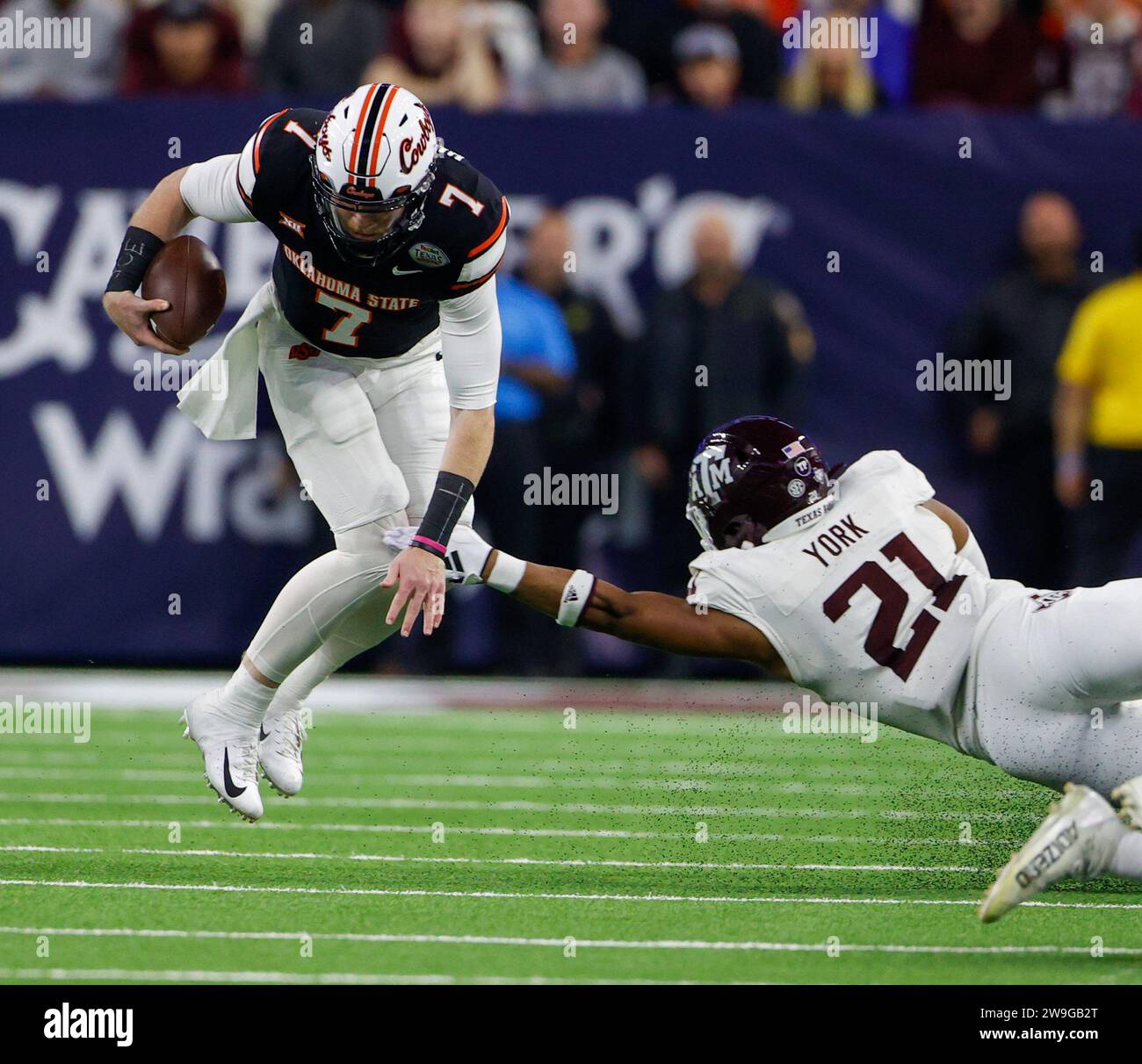 27 dicembre 2023: Il quarterback degli Oklahoma State Alan Bowman (7) si tuffa in avanti per yardage come il linebacker Texas A&M Taurean York (21) raggiunge un tackle durante la partita di TaxAct Texas Bowl tra gli Oklahoma State Cowboys e i Texas A&M Aggies il 27 dicembre 2023, a Houston. Oklahoma State Won, 31-23. (Immagine di credito: © Scott Coleman/ZUMA Press Wire) SOLO USO EDITORIALE! Non per USO commerciale! Foto Stock