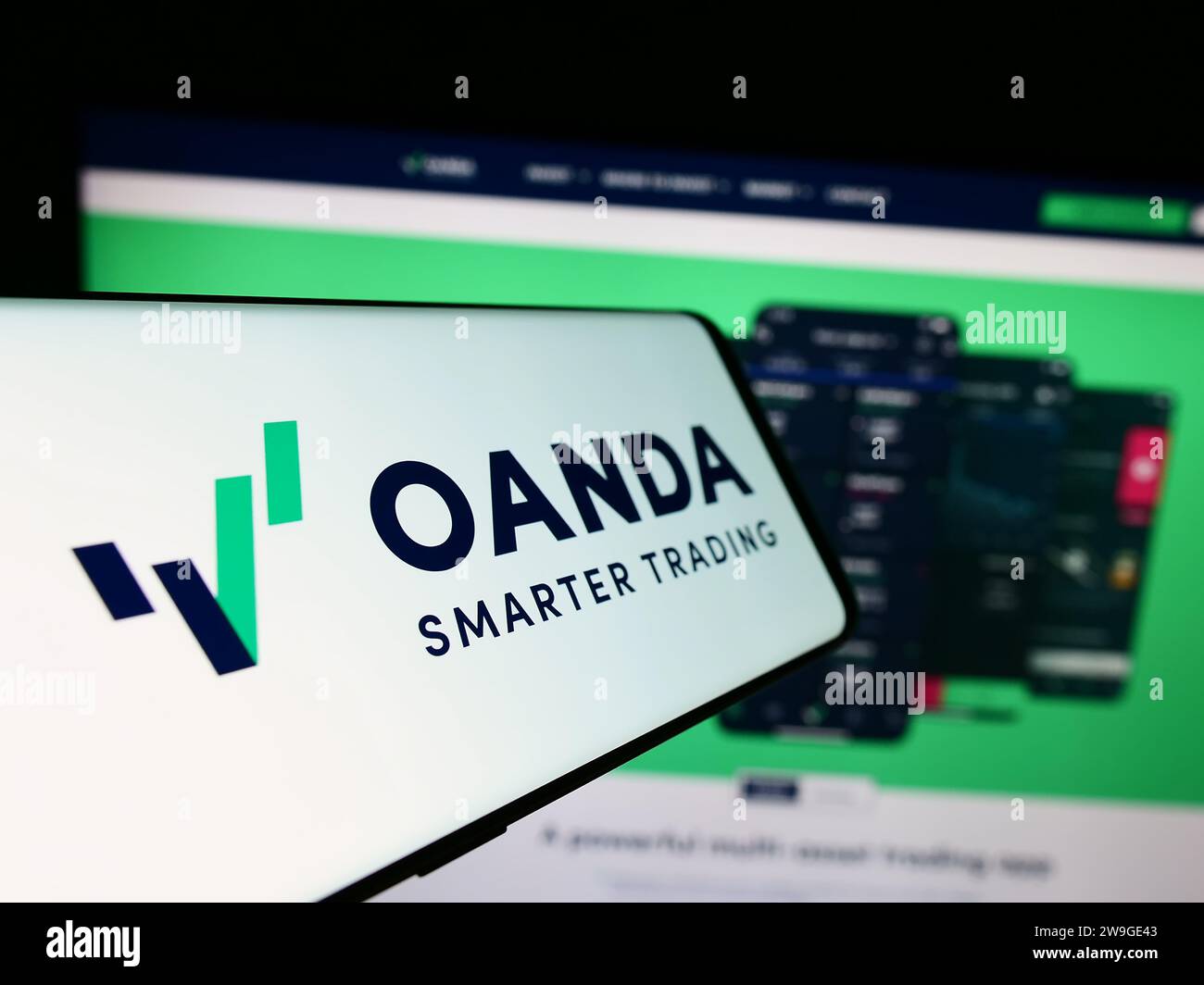Telefono cellulare con logo della società americana OANDA Business Information Services Inc. Davanti al sito Web. Mettere a fuoco il display centrale sinistro del telefono. Foto Stock