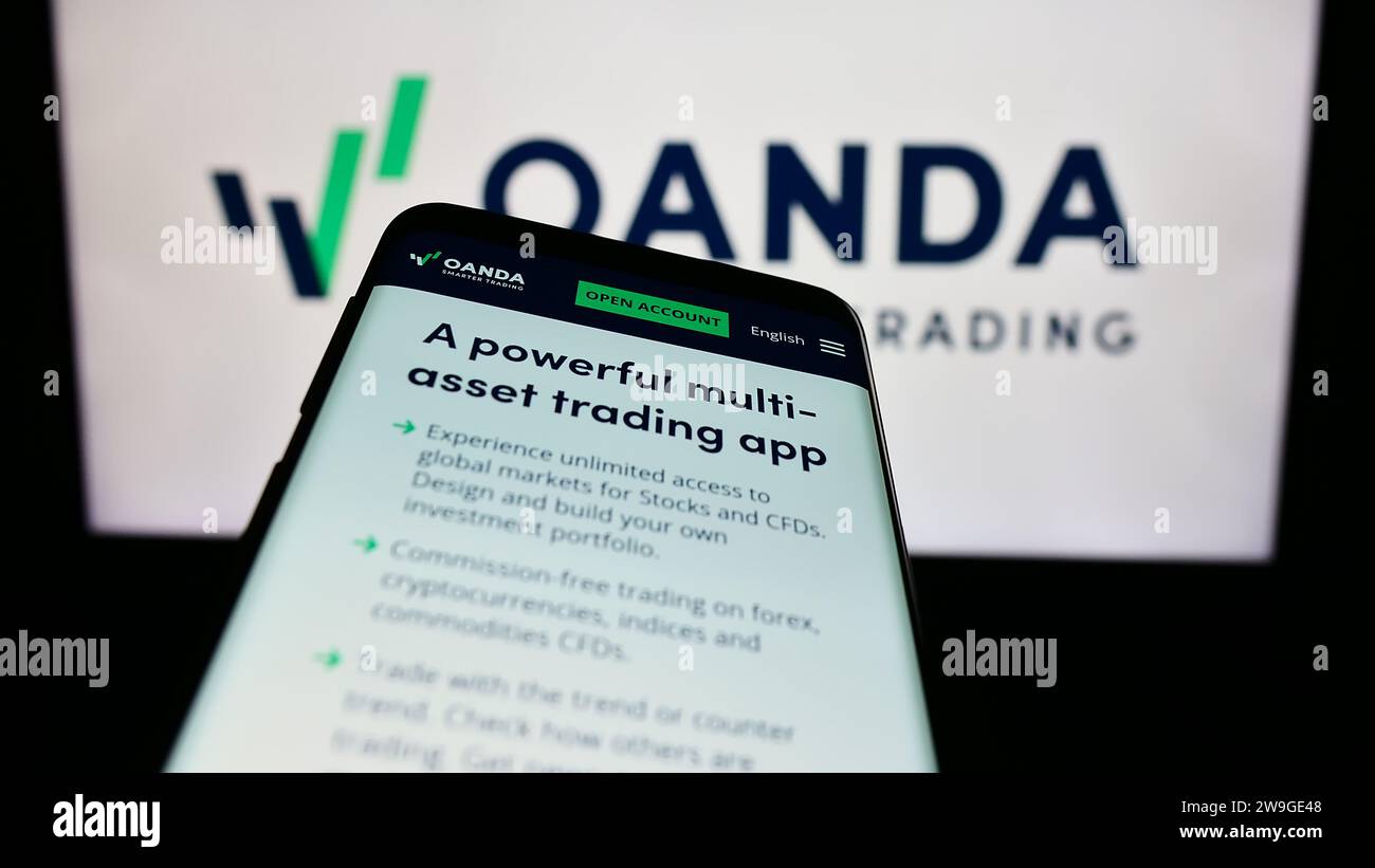 Smartphone con sito Web della società statunitense OANDA Business Information Services Inc. Davanti al logo aziendale. Mettere a fuoco in alto a sinistra sul display del telefono. Foto Stock
