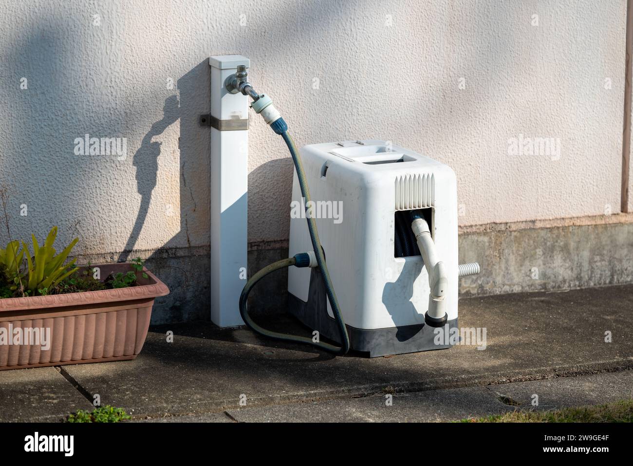 Avvolgitubo per acqua da giardino scatola di plastica portatile posizionata all'esterno della casa per il giardinaggio Foto Stock