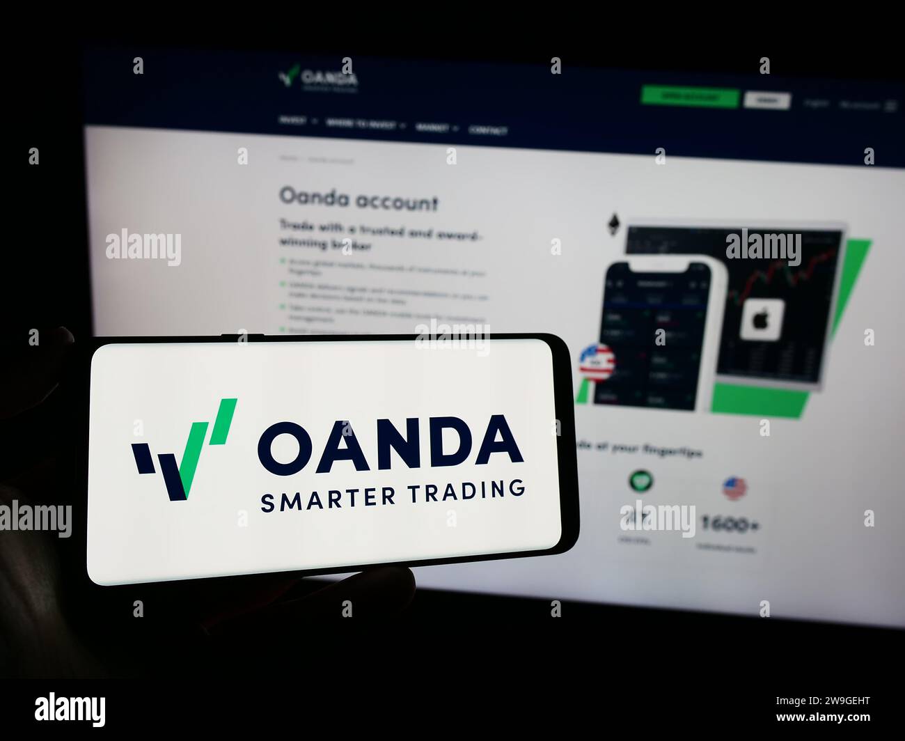 Persona che possiede un telefono cellulare con il logo della società americana OANDA Business Information Services Inc. Davanti alla pagina Web. Concentrarsi sul display del telefono. Foto Stock