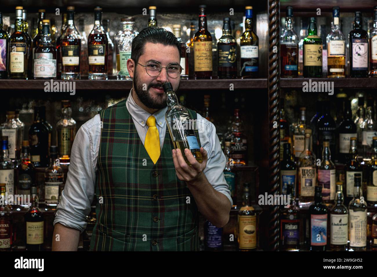 Bar man che nozza una bottiglia di whisky al Bertie's Whisky Bar, Fife Arms, Braemar, Scozia. Foto Stock
