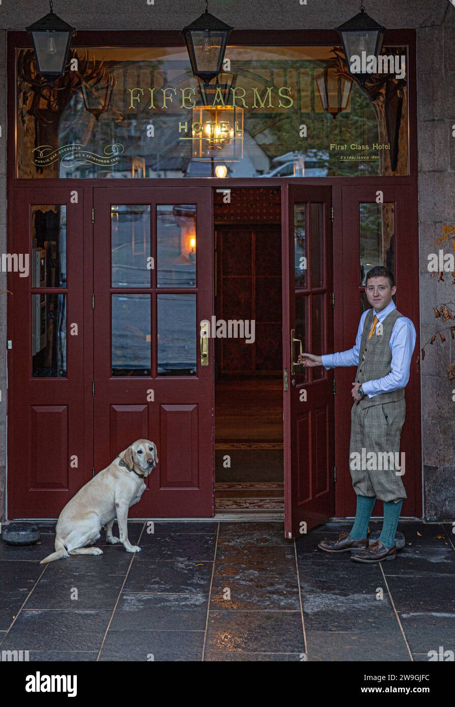Giovane portiere dell'hotel apre la porta al Fife Arms Hotel a Breamer, Aberdeenshire, Scozia. Foto Stock