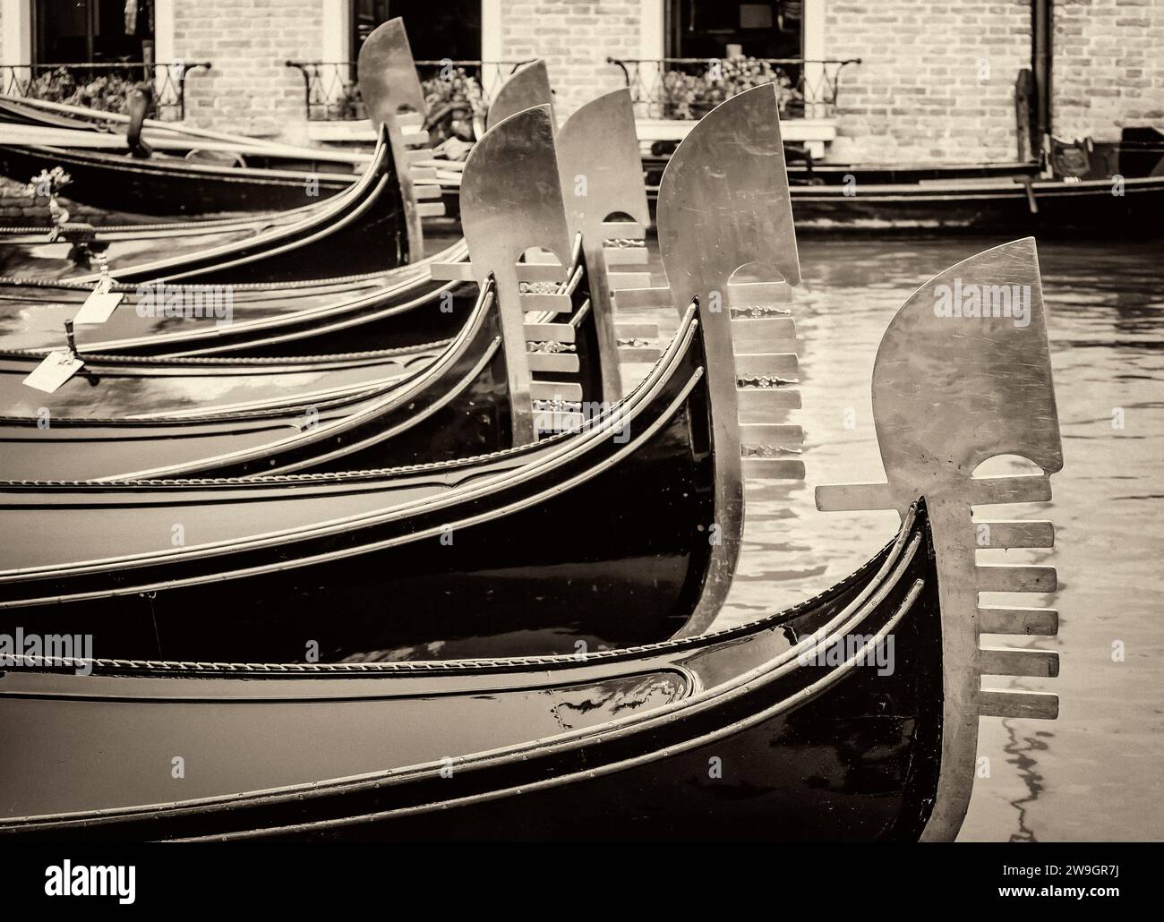Vista vintage in bianco e nero degli archi metallici delle tradizionali gondole veneziane ancorate in un canale nel quartiere di San Marco, Venezia, Italia Foto Stock