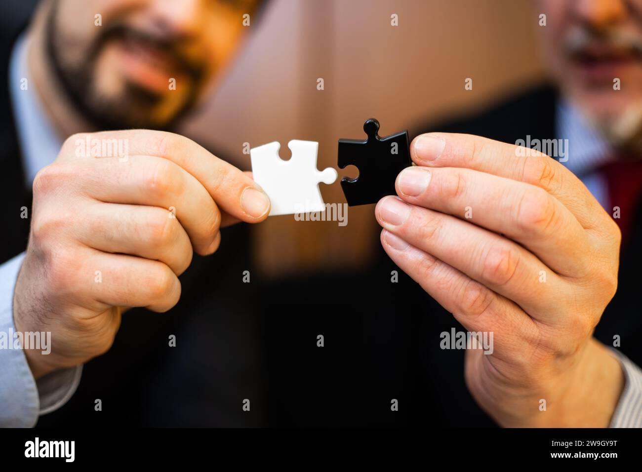 Primo piano di uomini d'affari caucasici di mezza età che collaborano e collegano strategicamente pezzi del puzzle per trovare una soluzione. Dimostrazione del teamwo Foto Stock