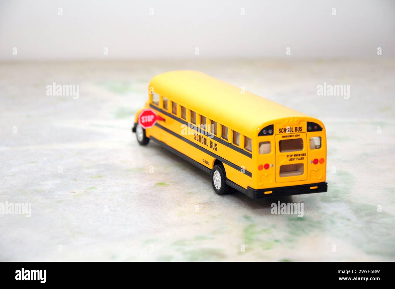 Scuolabus americano in miniatura di colore giallo standard con segnale di stop sul lato. Vista posteriore Foto Stock