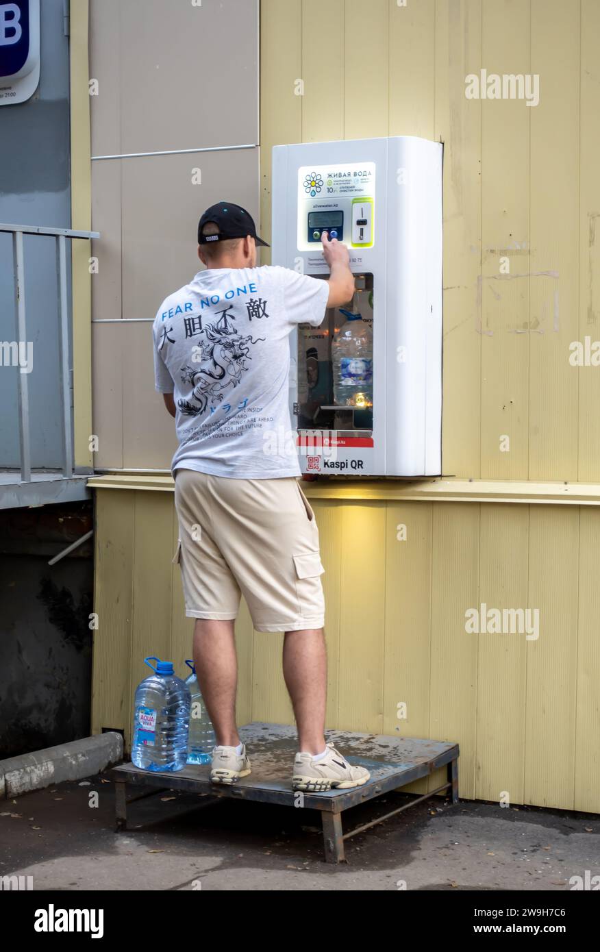 Un uomo che utilizza un distributore automatico di acqua potabile a pagamento ad Aqtobe, Kazakistan Foto Stock