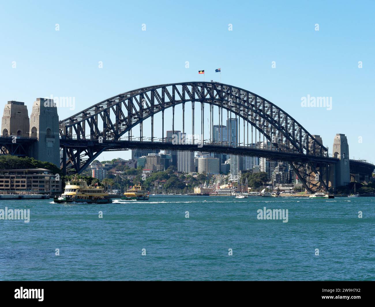 Vista del famoso Sydney Harbour Bridge che attraversa il porto, con North Sydney sullo sfondo e un traghetto che passa Foto Stock