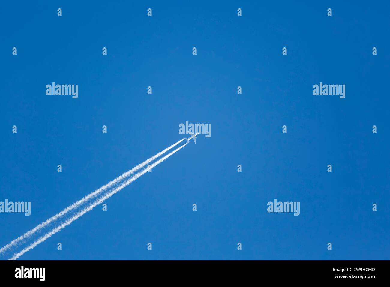 L'inquinamento atmosferico causato dall'aereo contrasta durante il viaggio in alto in un cielo blu cristallino Foto Stock
