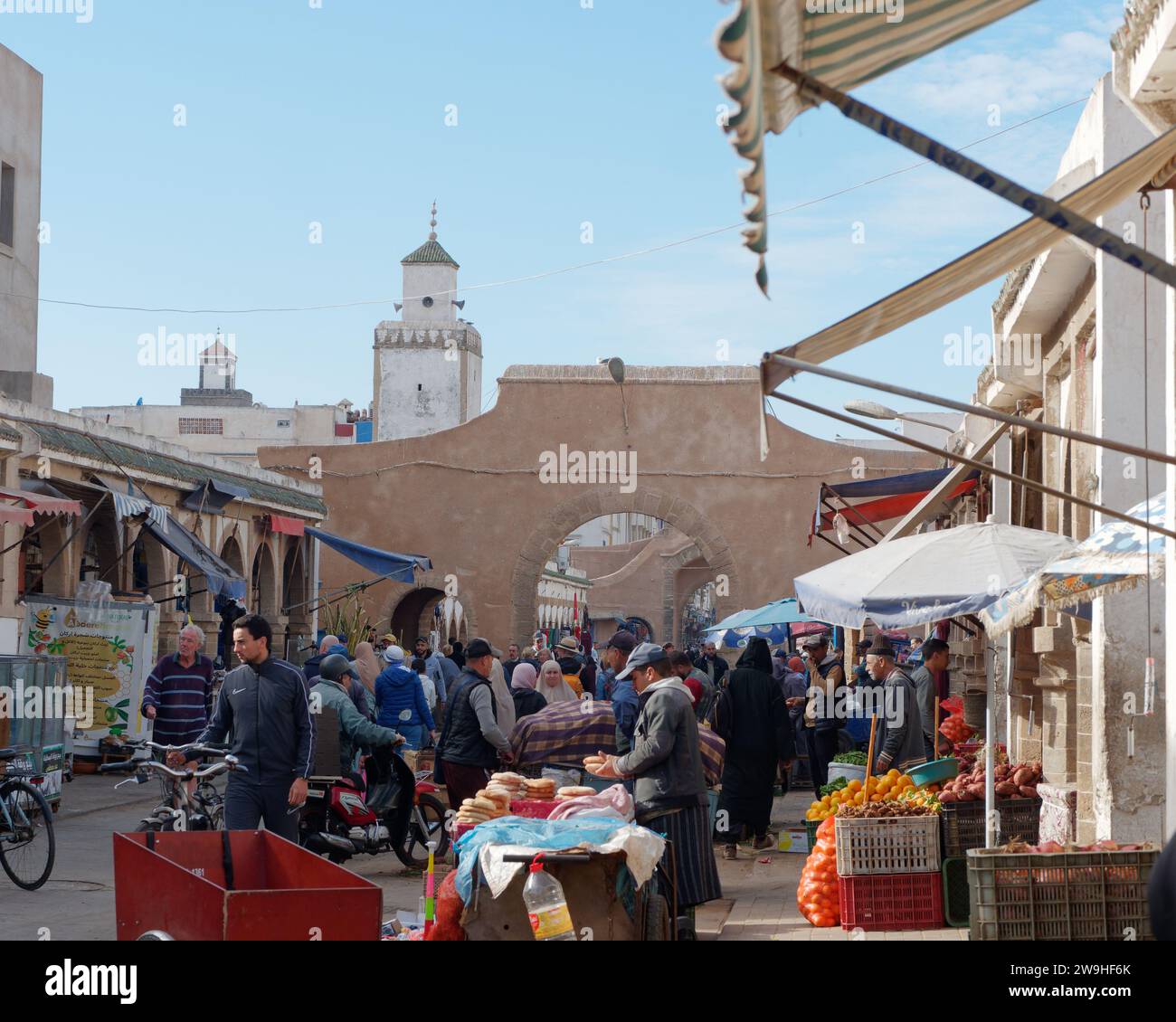 Vivace strada principale e mercato nella Medina con arco nella città di Essaouira, Marocco. 28 dicembre 2023 Foto Stock