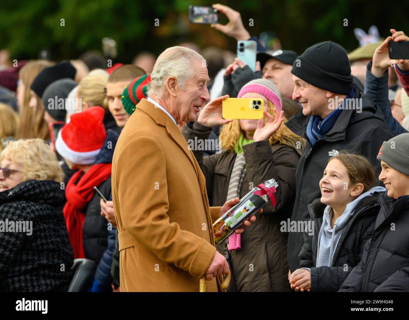 Il re saluta i benestanti e riceve un regalo dopo aver partecipato al servizio natalizio nella chiesa di Santa Maria Maddalena, Sandringham. 25 dicembre 2023 Foto Stock