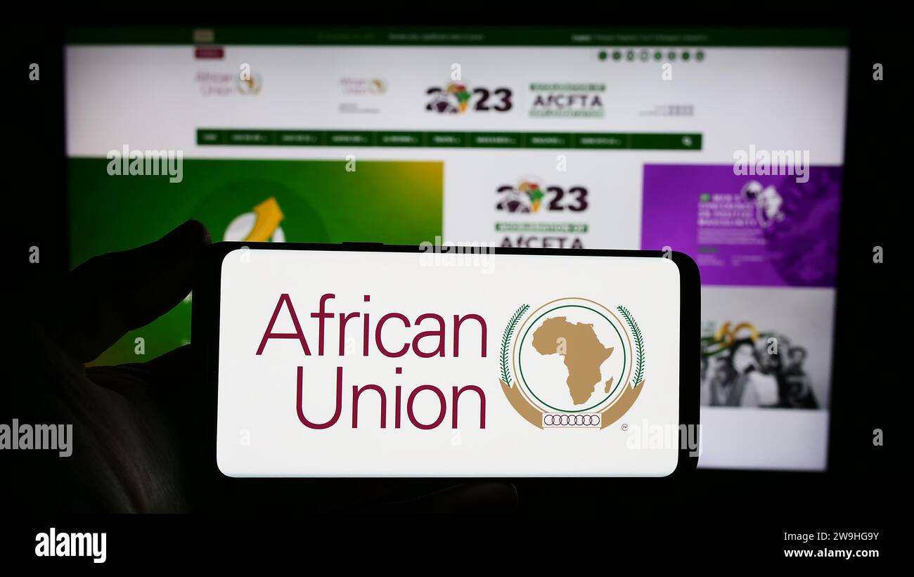 Persona che possiede uno smartphone con il logo dell'organizzazione continentale dell'Unione africana (UA) davanti al sito web. Concentrarsi sul display del telefono. Foto Stock