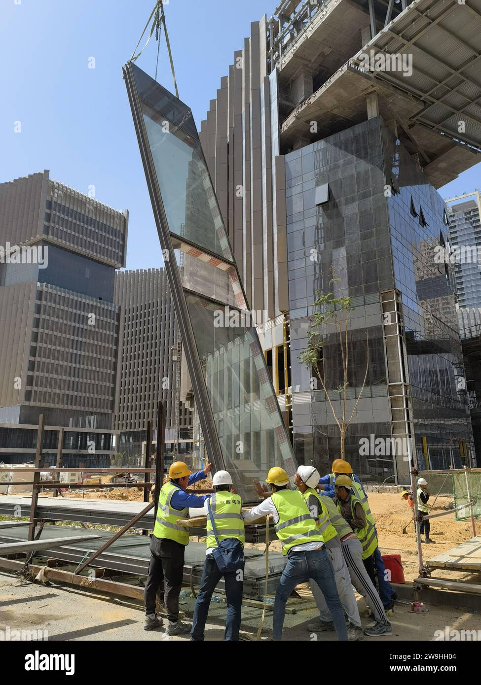 (231228) -- CAIRO, 28 dicembre 2023 (Xinhua) -- questa foto del cellulare scattata il 4 giugno 2023 mostra i lavoratori che stanno sollevando le pareti del sipario nel quartiere centrale degli affari (CBD) della nuova capitale amministrativa dell'Egitto, a 45 chilometri a est del Cairo, in Egitto. Nel vasto e torrido deserto del Nord Africa, i lavoratori cinesi ed egiziani stanno lavorando contro il tempo per vestire un gruppo di grattacieli appena eretti in pareti di vetro fabbricate in Cina. la nuova capitale non è solo un progetto chiave della China-Proposed Belt and Road Initiative, ma anche il più grande progetto costruito da compani cinesi Foto Stock