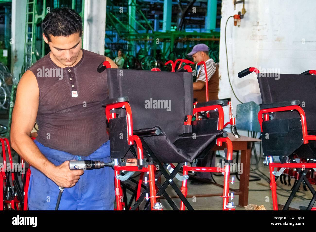 Negozio di sedie a rotelle cubane. Un lavoratore che salda i giunti di una sedia a rotelle durante il processo di produzione in una fabbrica. Foto Stock