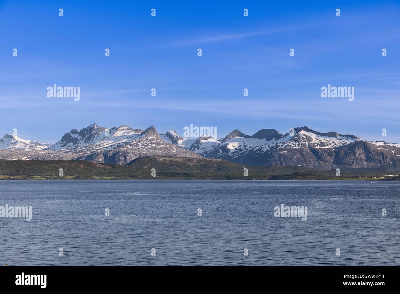 Vista estiva delle montagne innevate di Saltfjorden sotto un cielo blu, vicino a Bodo nell'arcipelago delle Lofoten, Norvegia Foto Stock