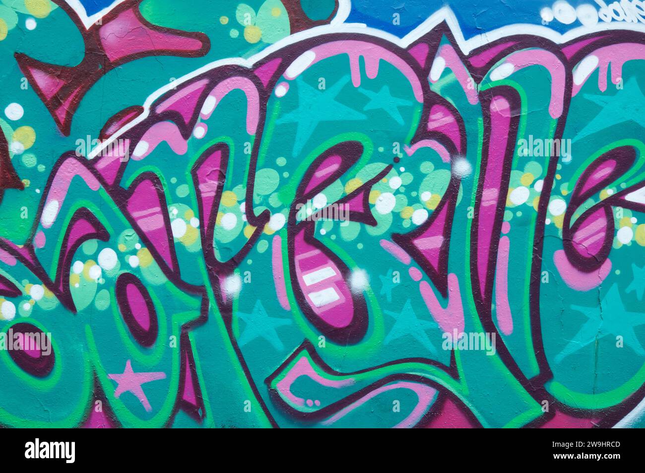 Street art urbana. Vivide lettere graffiti di colore verde e magenta, dipinte su una parete sotto il cavalcavia Fleetsbridge a Poole. Dorset, Inghilterra, Regno Unito. Foto Stock