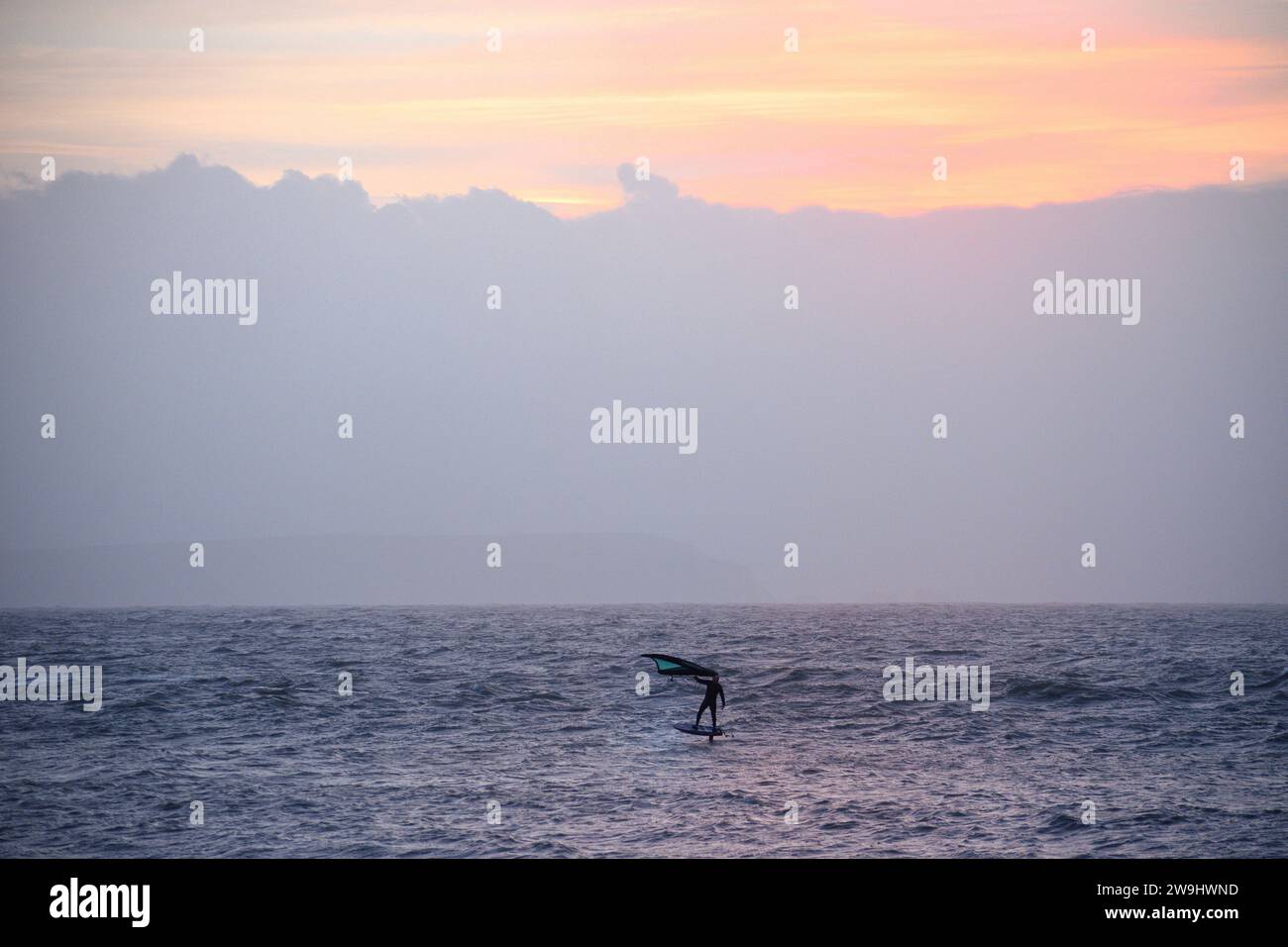 Il foil boarder da solo all'alba a Avon Beach nel Dorset, Regno Unito Foto Stock