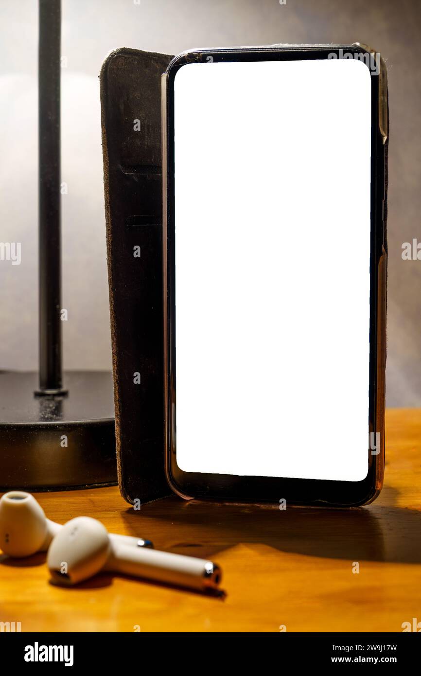 Smartphone con custodia ribaltabile e schermo bianco vuoto sul comodino, percorso di ritaglio Foto Stock