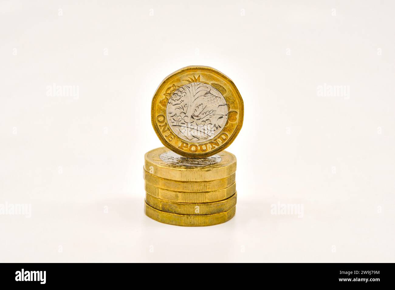Moneta britannica da una sterlina in cima a una colonna di monete isolate su un semplice sfondo bianco. Concetto finanziario. Foto Stock