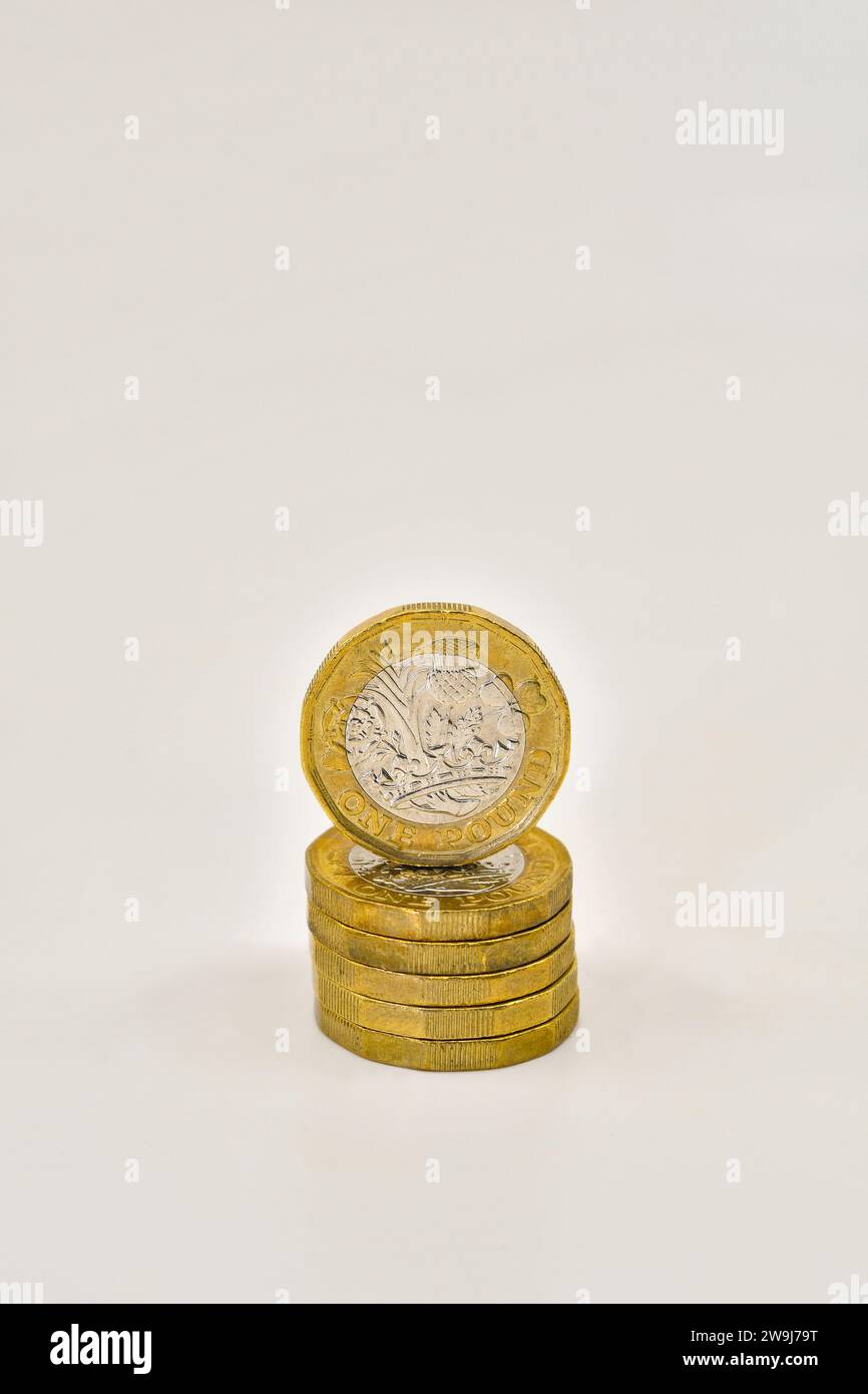 Moneta britannica da una sterlina in cima a una colonna di monete isolate su un semplice sfondo bianco. Concetto finanziario. Foto Stock