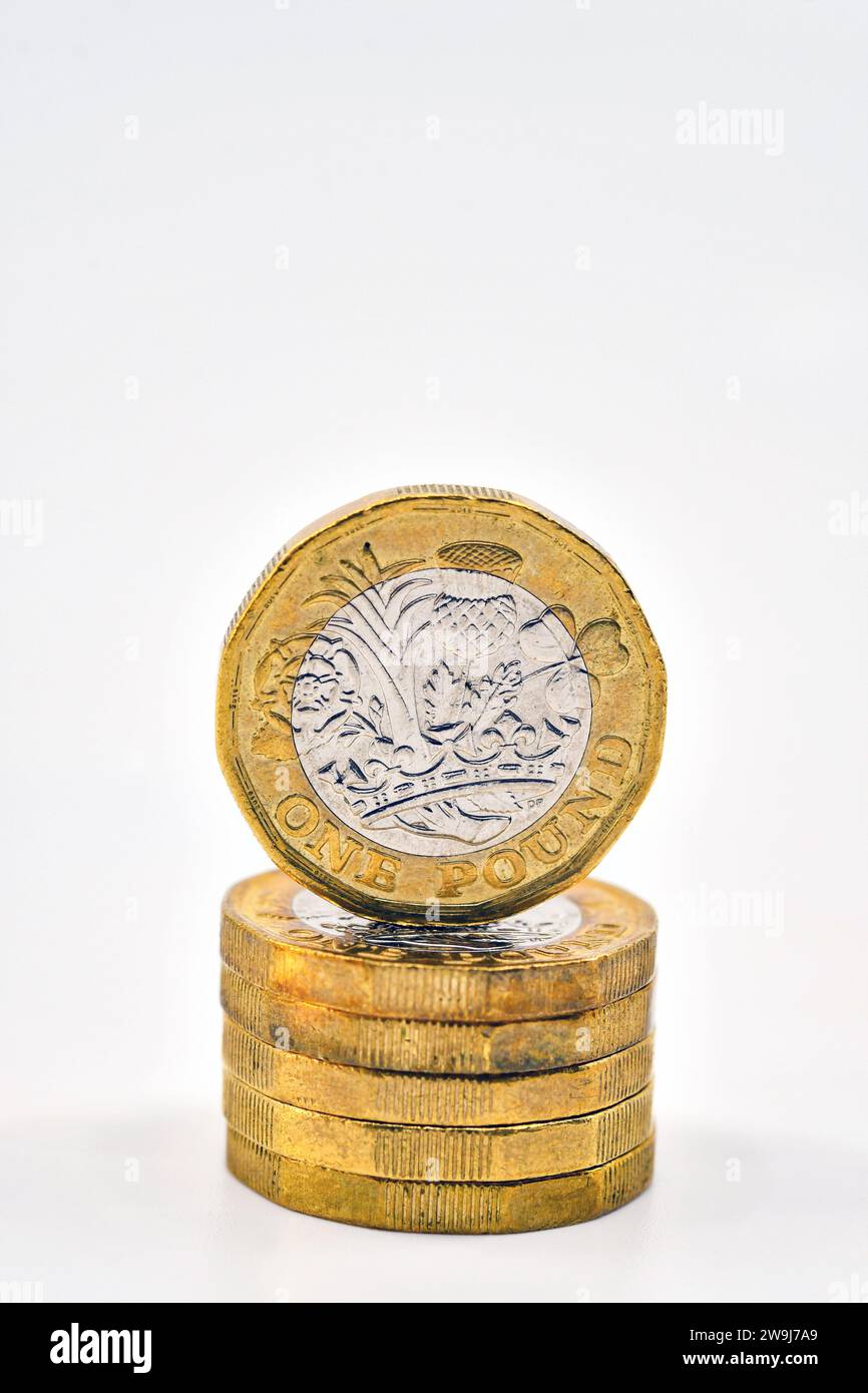 Moneta britannica da una sterlina in cima a una colonna di monete isolate su un semplice sfondo bianco. Concetto finanziario. Foto Stock