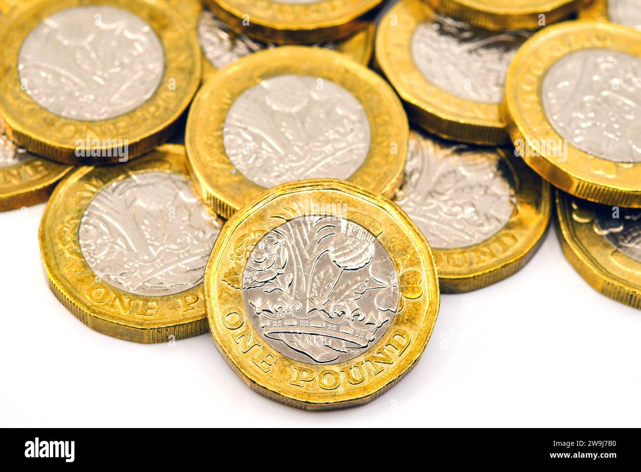 Vista ravvicinata delle monete britanniche da una sterlina su un semplice sfondo bianco. Concetto finanziario. Foto Stock