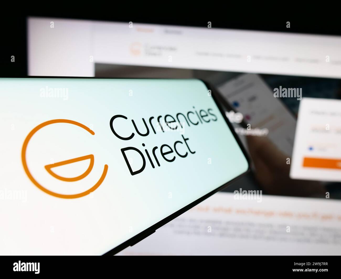 Telefono cellulare con logo della società britannica di trasferimento di denaro Currencies Direct Ltd. Davanti al sito Web. Mettere a fuoco il display centrale sinistro del telefono. Foto Stock
