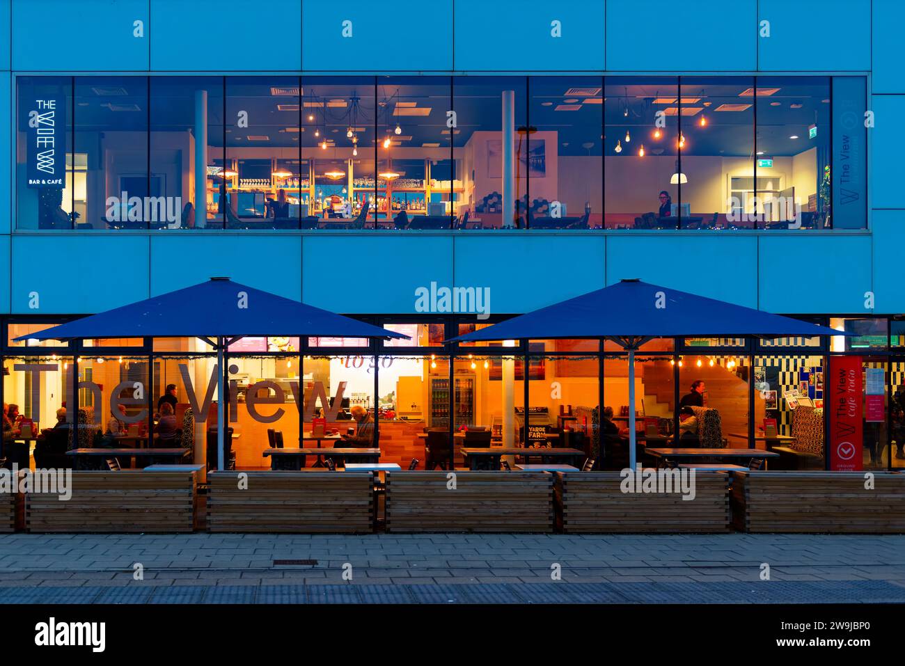 Teignmouth, Devon. Il Pavilion Cafe e bar si trova su un alto edificio a due piani con i commensali all'interno. Fotografia notturna con edificio illuminato all'interno. Foto Stock