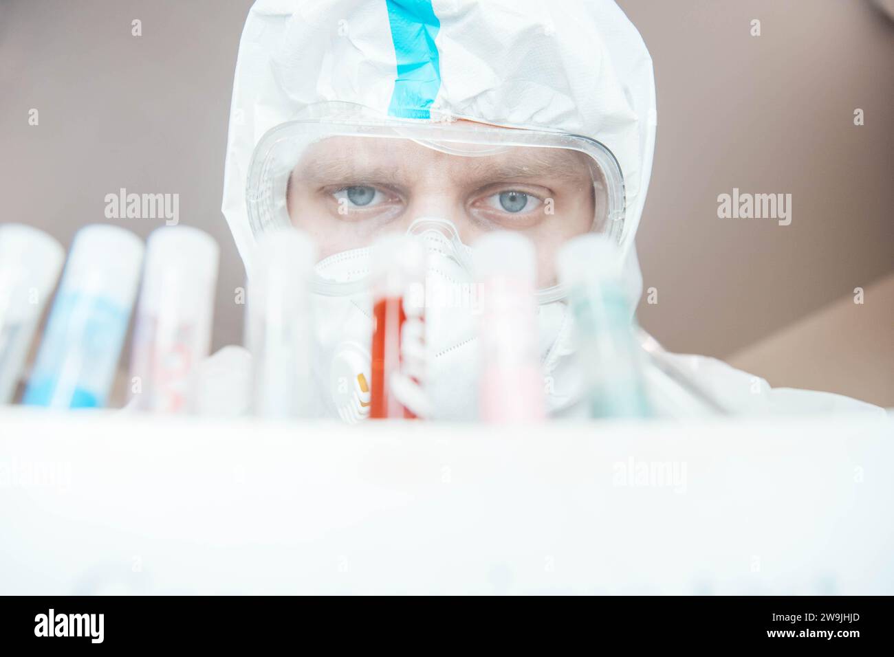 Medico scienziato in uniforme esamina una provetta con sangue in un laboratorio Foto Stock