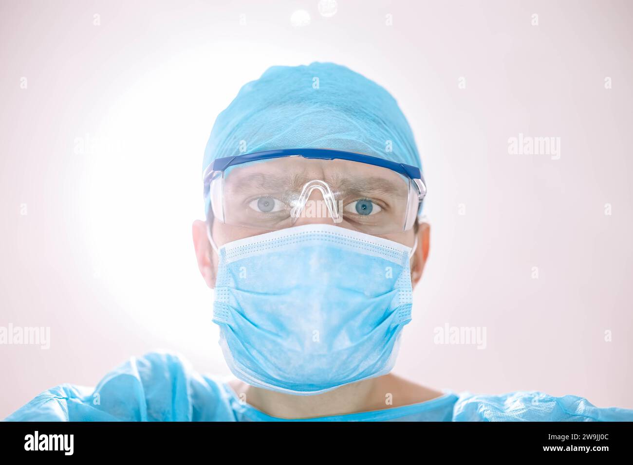 Medico chirurgo maschio in sala operatoria che guarda il paziente alla telecamera Foto Stock