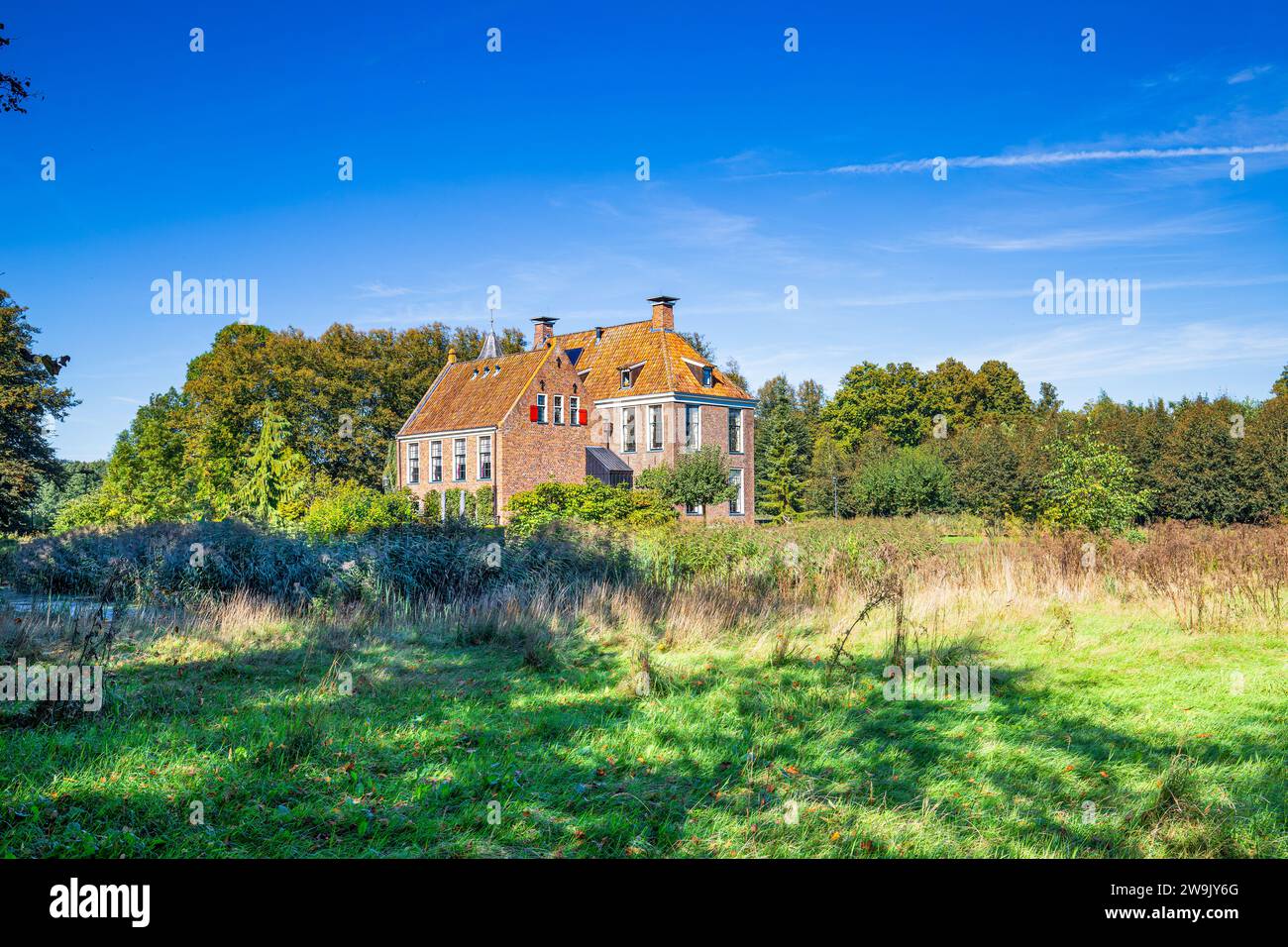 Paesaggio con mattoni fortificati Huis te Wedde nel villaggio di Wedde, in provincia di Groningen, con persiane per finestre e tegole arancio realizzate in b Foto Stock