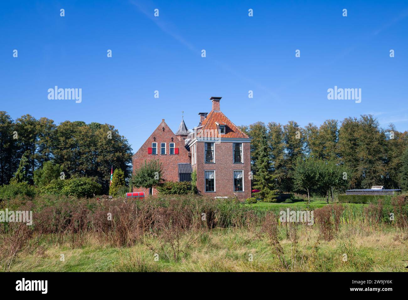 Paesaggio con mattoni fortificati Huis te Wedde nel villaggio di Wedde, in provincia di Groningen, con persiane per finestre e tegole arancio realizzate in b Foto Stock