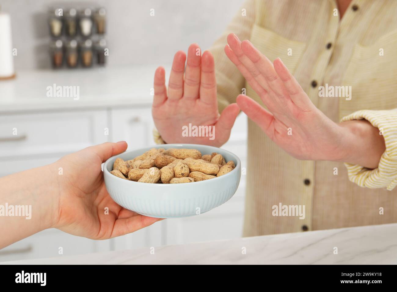 Donna che soffre di allergie alimentari che rifiuta di offrire arachidi dal suo amico a casa, primo piano Foto Stock
