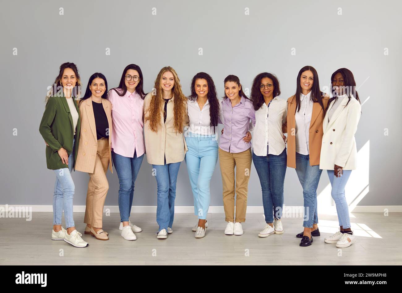 Gruppo di donne amiche e dipendenti aziendali felici e diversificate che guardano la fotocamera su sfondo grigio. Foto Stock
