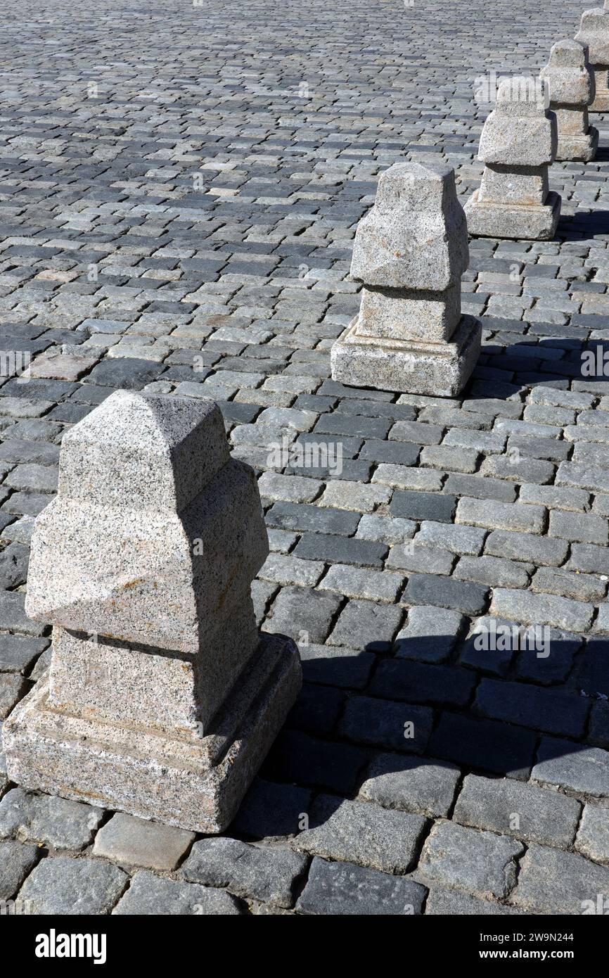 Barriera dalla lunga linea di piramidi di granito sulla vista laterale della pavimentazione stradale Foto Stock