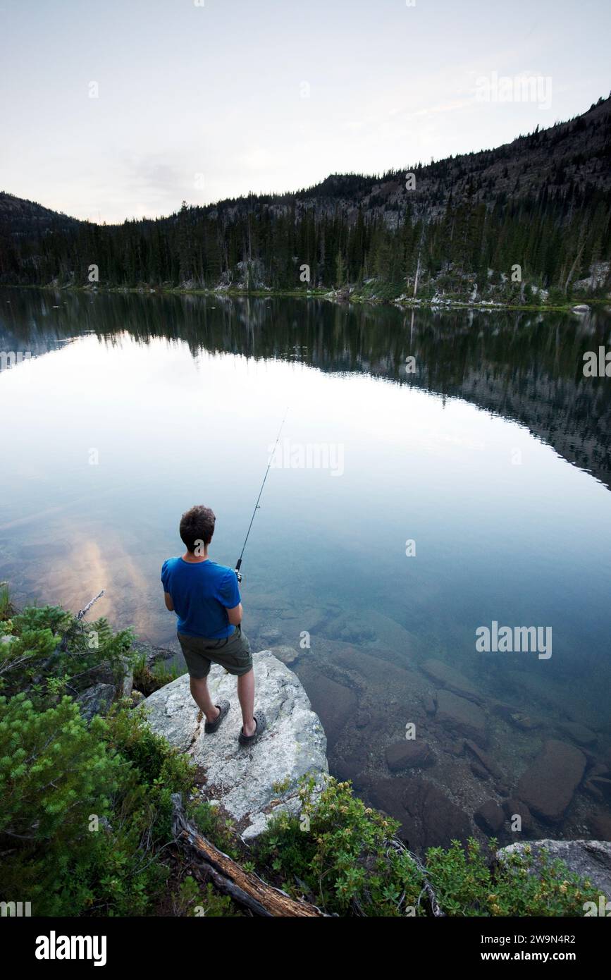 Un ragazzo pesca nel lago Douglas al tramonto il 3° giorno del suo trekking attraverso l'Eagle Cap Wilderness nel nord-est dell'Oregon. Foto Stock