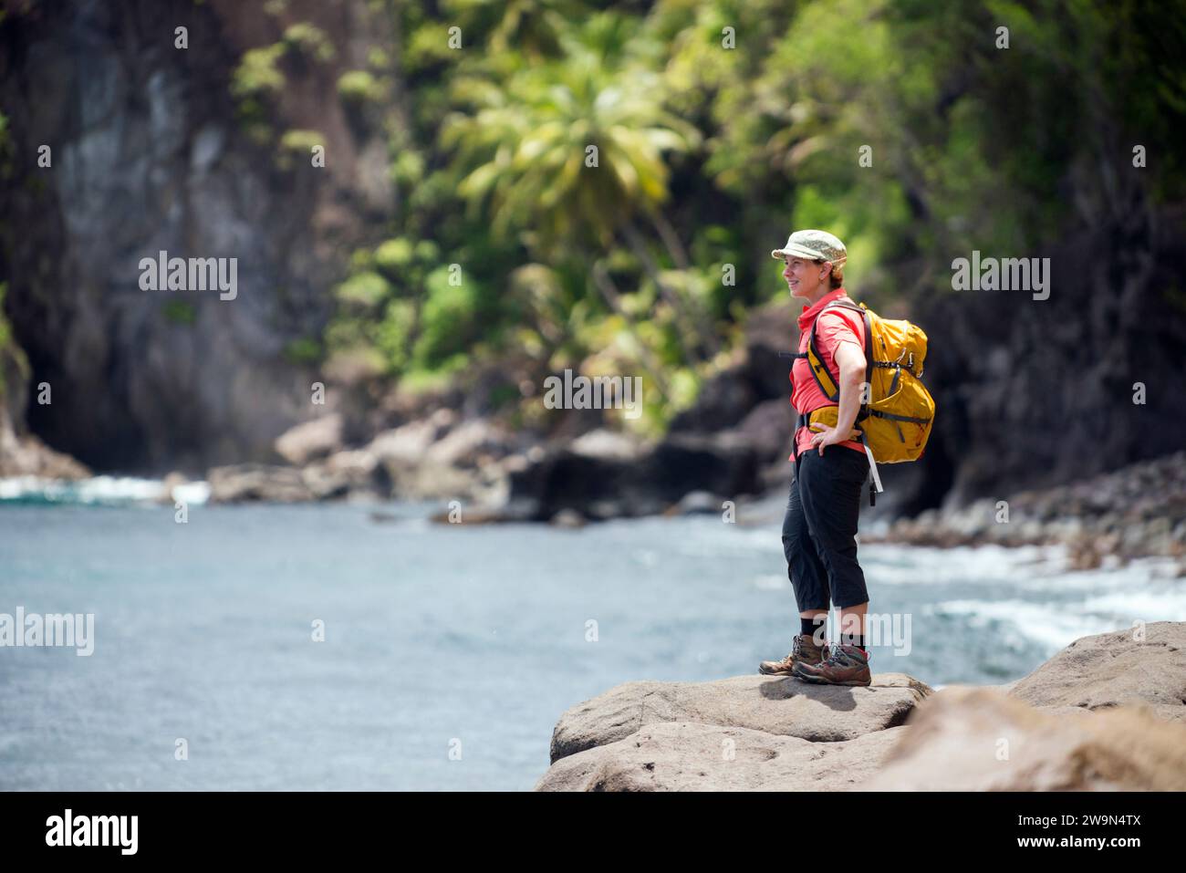 Un viaggiatore con zaino in spalla si gode la vista del segmento 14 del Waitukubuli National Trail sulla riva del Mar dei Caraibi sull'isola di Dominica. Foto Stock