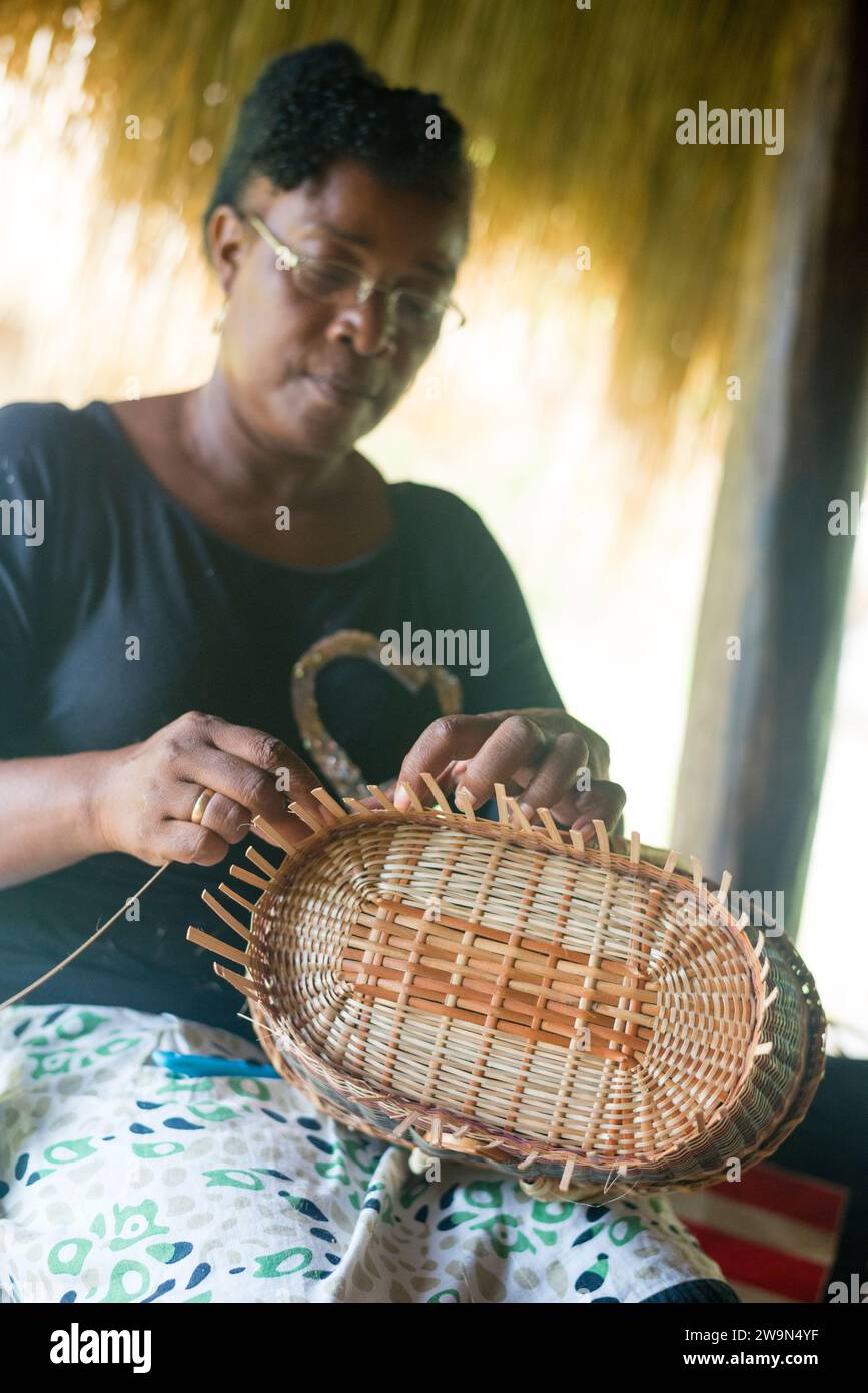 Una donna intreccia un cesto tradizionale nel Touna Kalinago Heritage Village, nel territorio di Kalinago, sull'isola caraibica di Dominica. Foto Stock