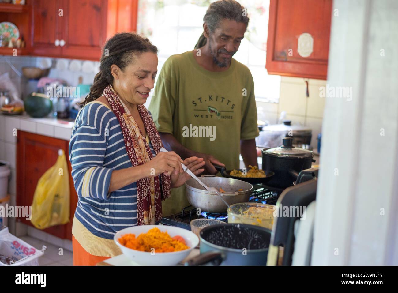 Una donna rastafariana e suo marito cucinano un tradizionale pasto rastafariano nella loro casa sull'isola caraibica di Dominica. Foto Stock