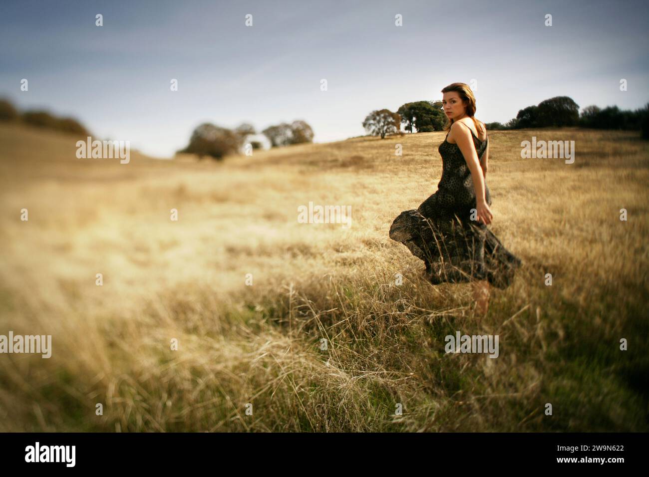 Una donna che cammina in un campo asciutto guarda indietro, nel nord della California. (Fuoco selettivo) Foto Stock