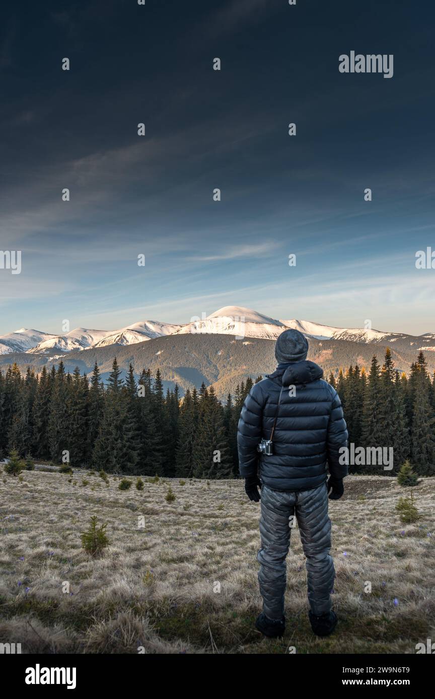 Giovane uomo con macchina fotografica che si gode la vista delle montagne all'alba. Foto Stock